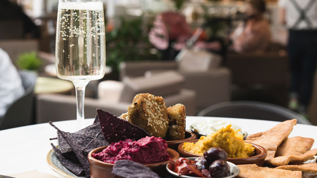 A plate full of food in the cafe bar alongside a glass flute of bubbly champagne.