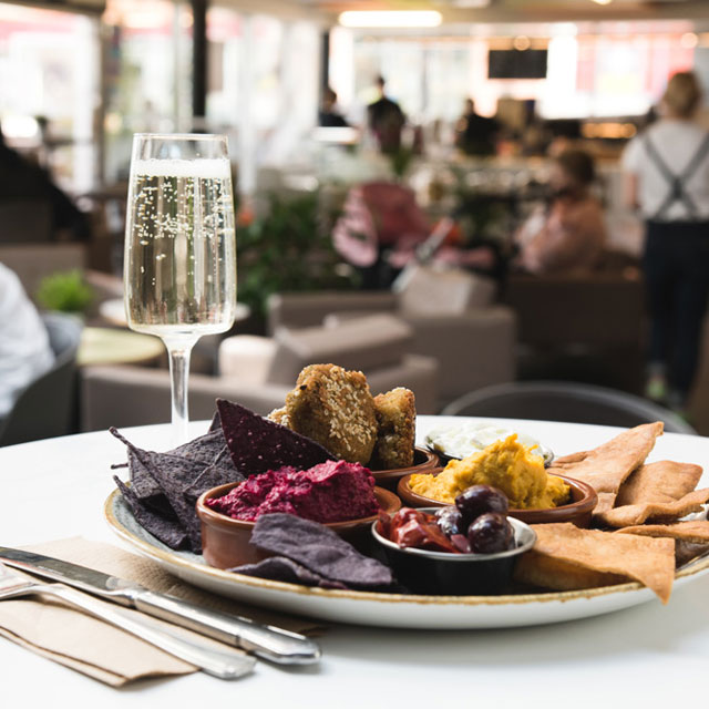 A plate full of food in the cafe bar alongside a glass flute of bubbly champagne.