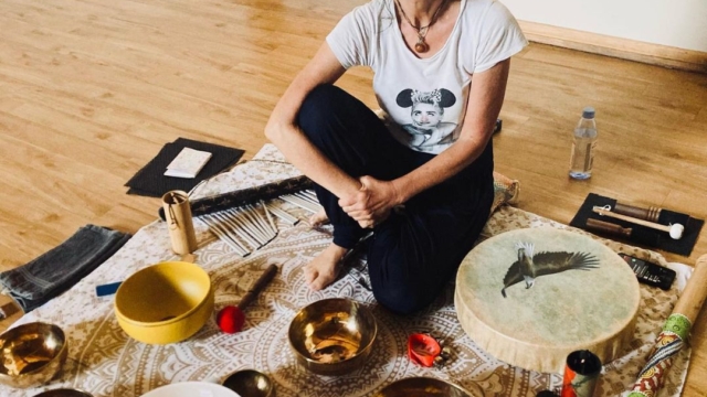 Someone sat on a mat with a variety of sound bath instruments.