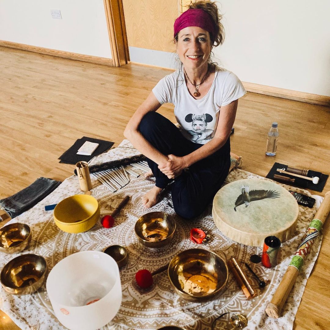 Someone sat on a mat with a variety of sound bath instruments.