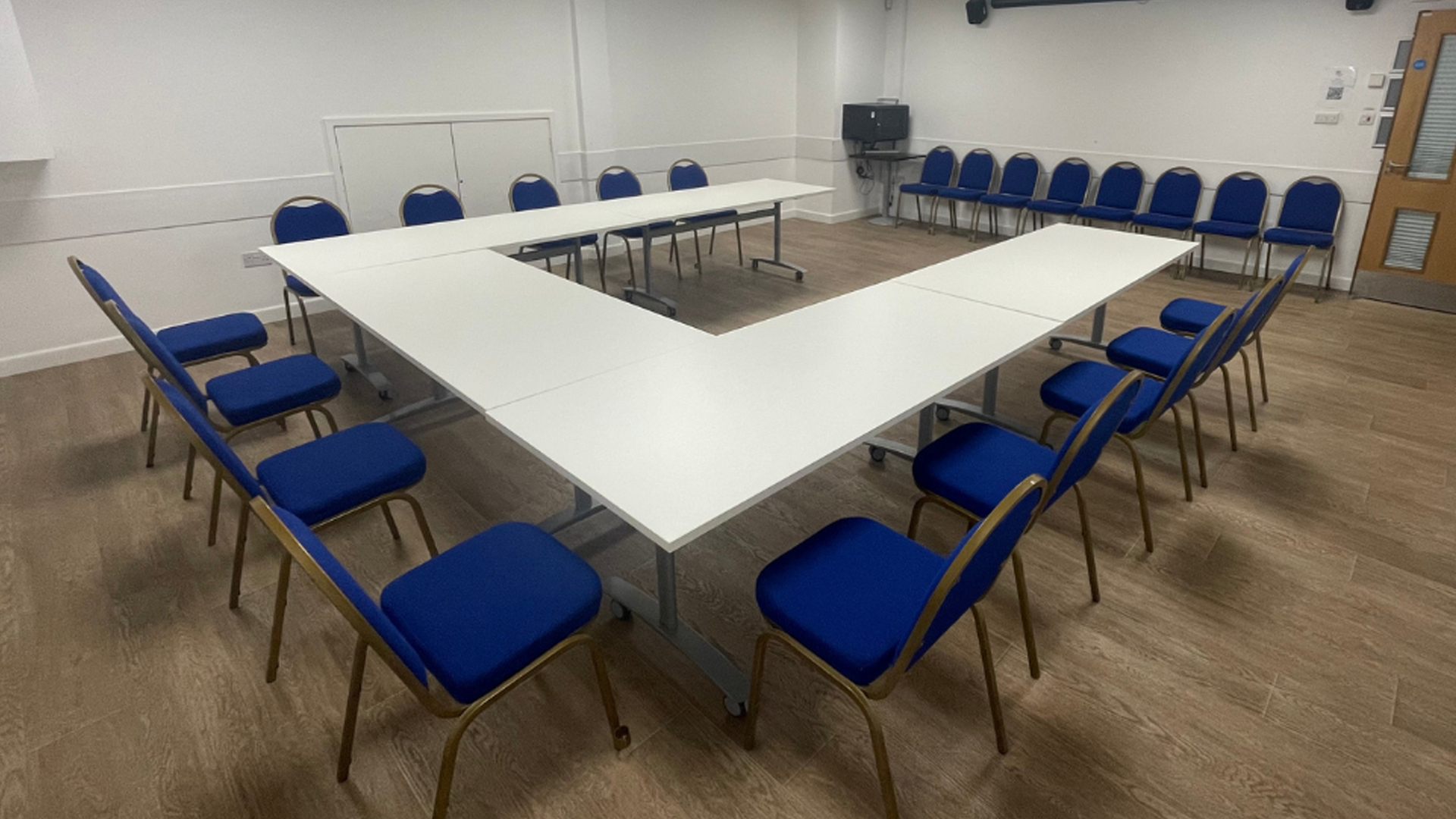 A meeting room space with a horseshoe shaped table and lots of chairs.