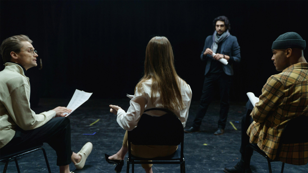 A group of people sat on chairs rehearsing.