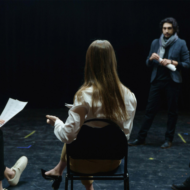 A group of people sat on chairs rehearsing.
